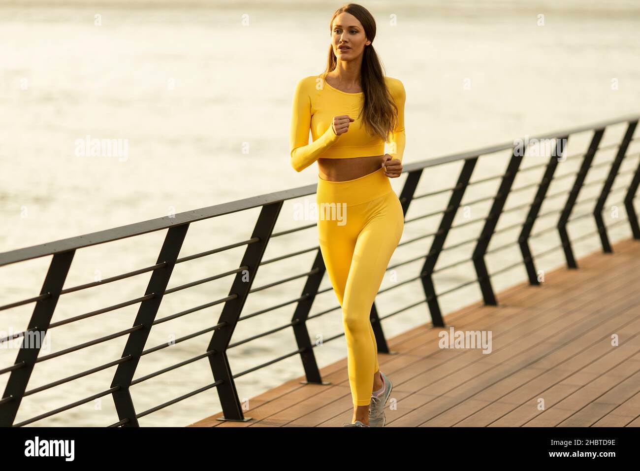 Bella giovane donna che corre esercizio sul molo lungo il fiume Foto Stock