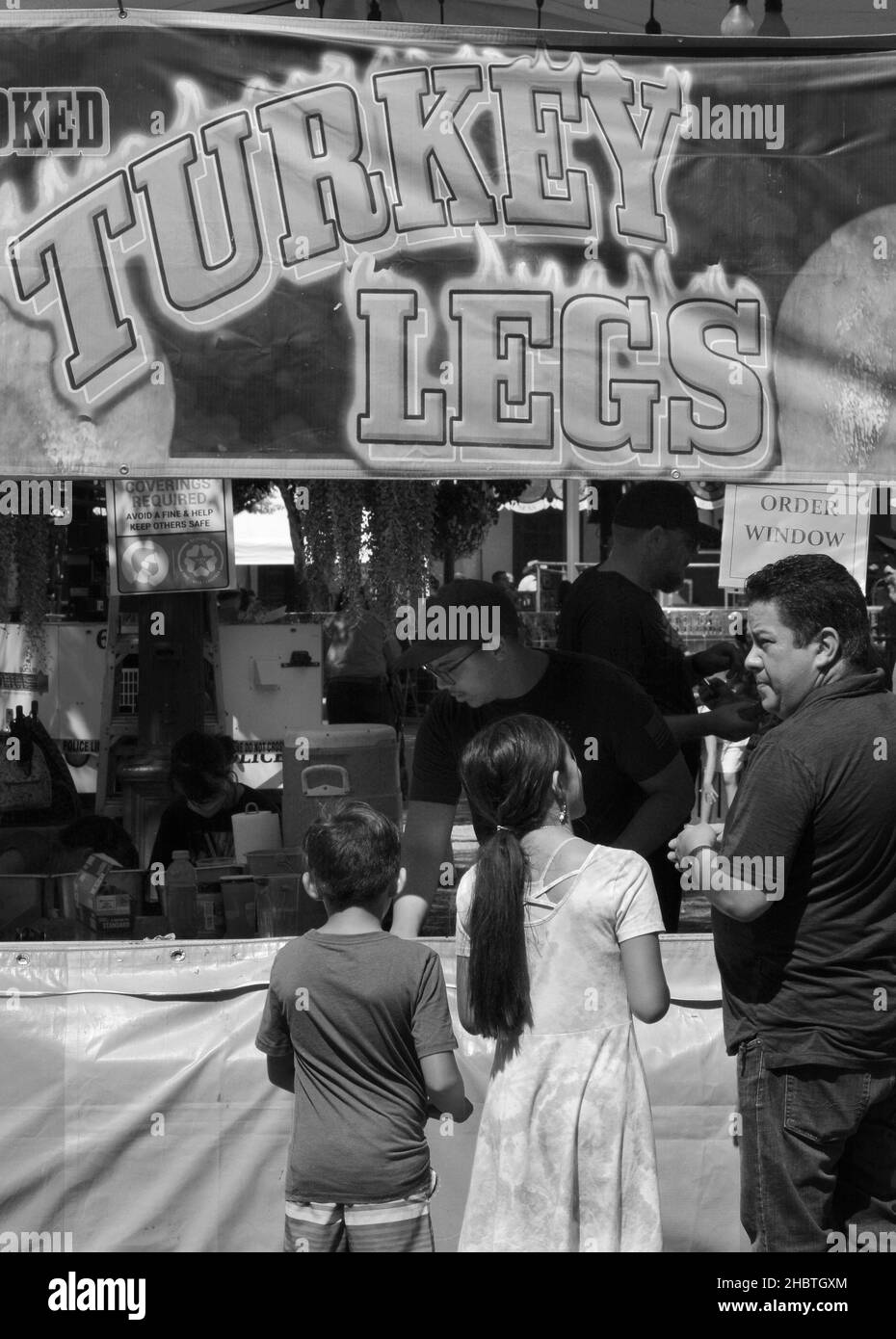 Un padre acquista zampe di tacchino affumicate per due figli da un fornitore di cibo in un festival all'aperto a Santa Fe, New Mexico. Foto Stock