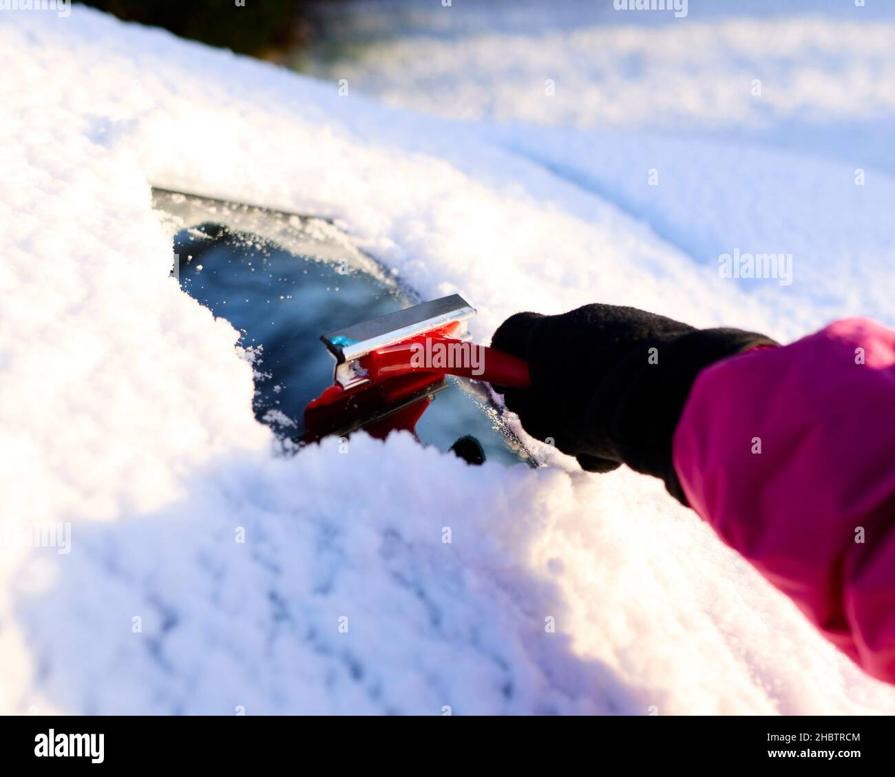 Il conducente sgombrare la neve dal parabrezza Foto Stock