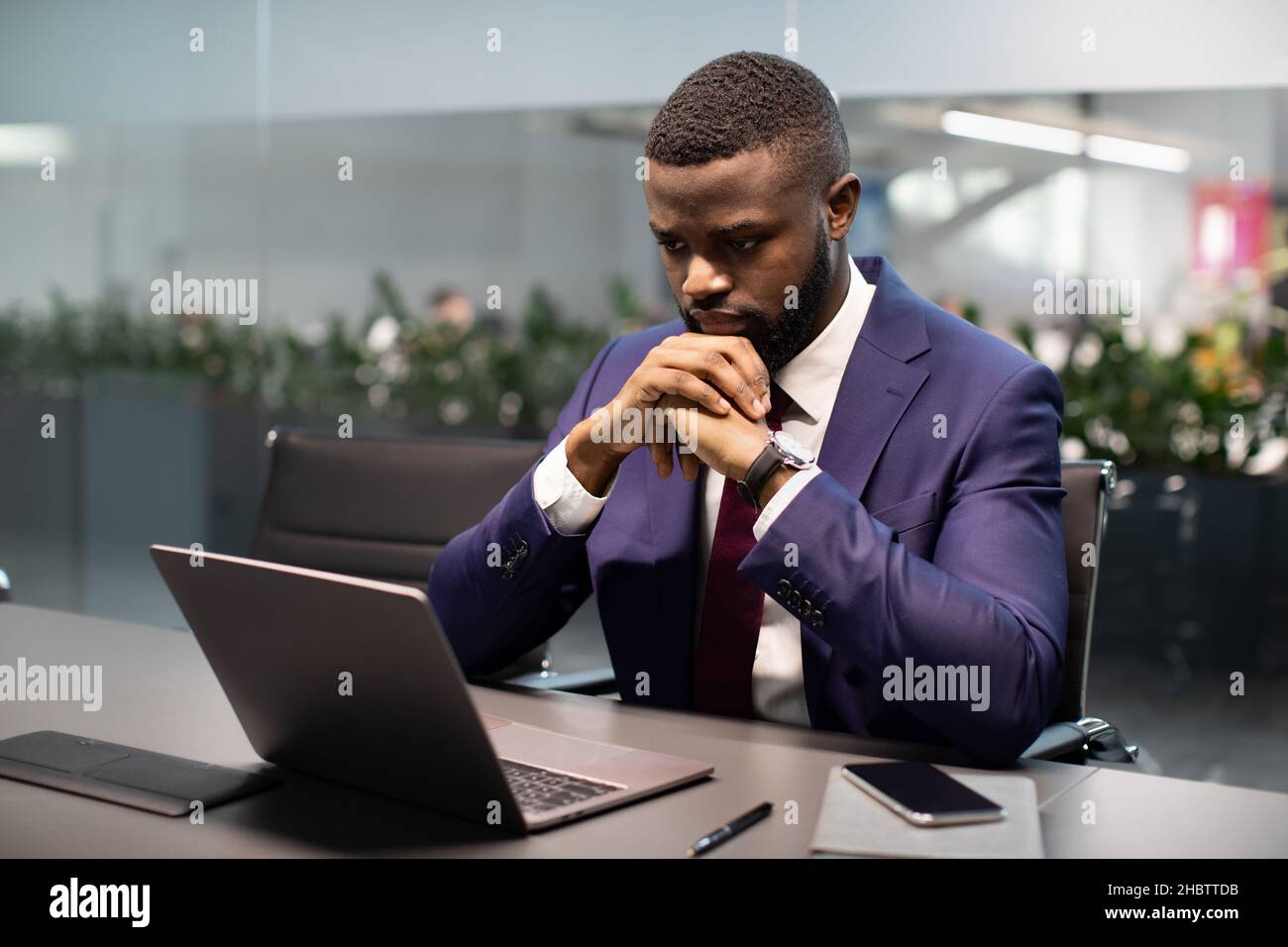 Pensivo giovane imprenditore afroamericano che lavora su laptop Foto Stock