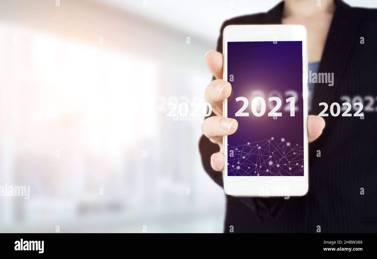 anno nuovo 2021. Smartphone bianco con hologram digitale 2021 su sfondo sfocato chiaro. Concept inizio nuovo anno 2022. Foto Stock