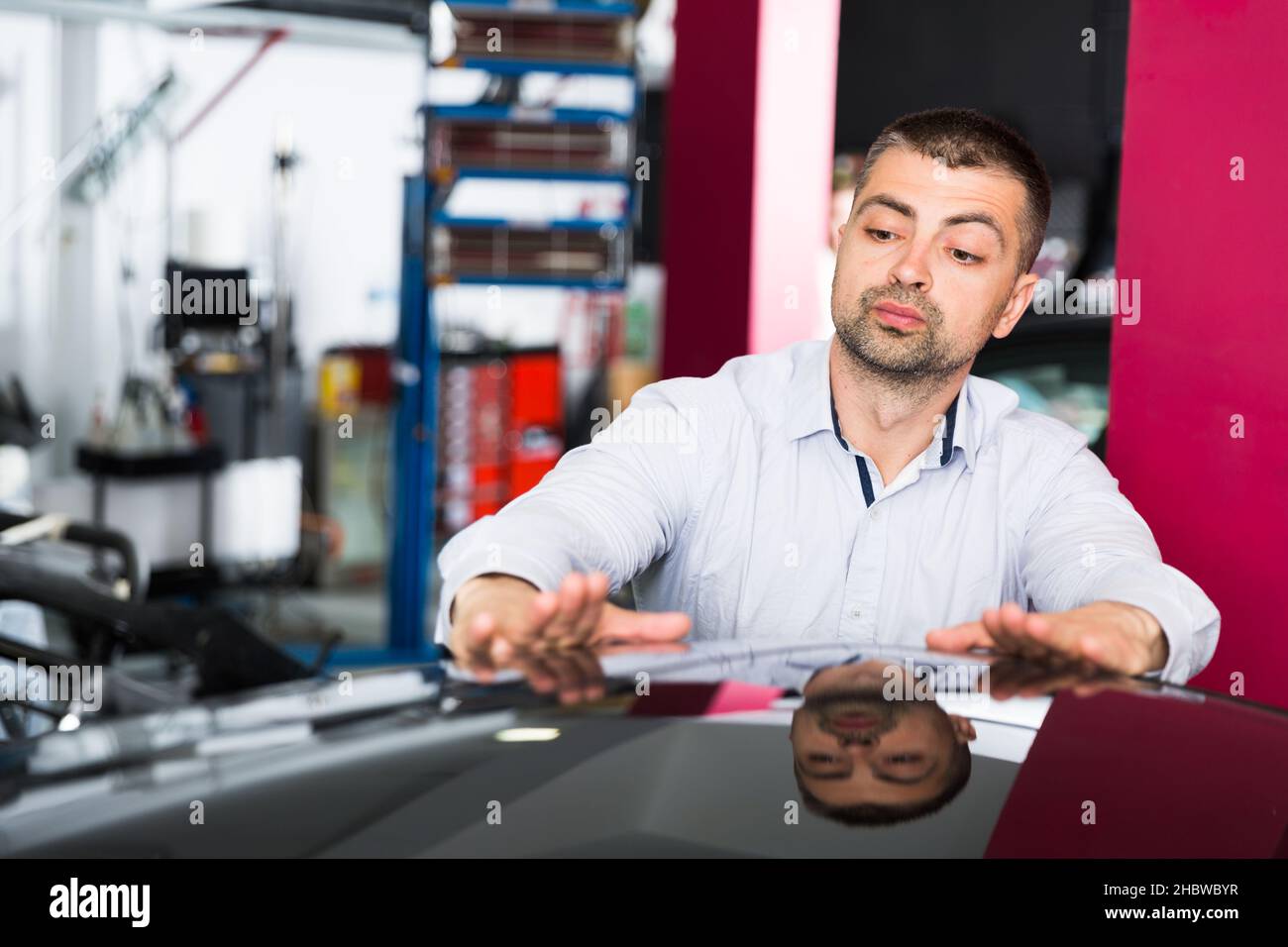 Cliente maschio che ispeziona la qualità di verniciatura del veicolo Foto Stock
