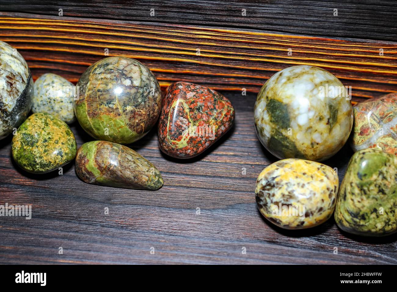 Collezione di pietre lavorate di diversi colori - magmatite - su sfondo ligneo Foto Stock