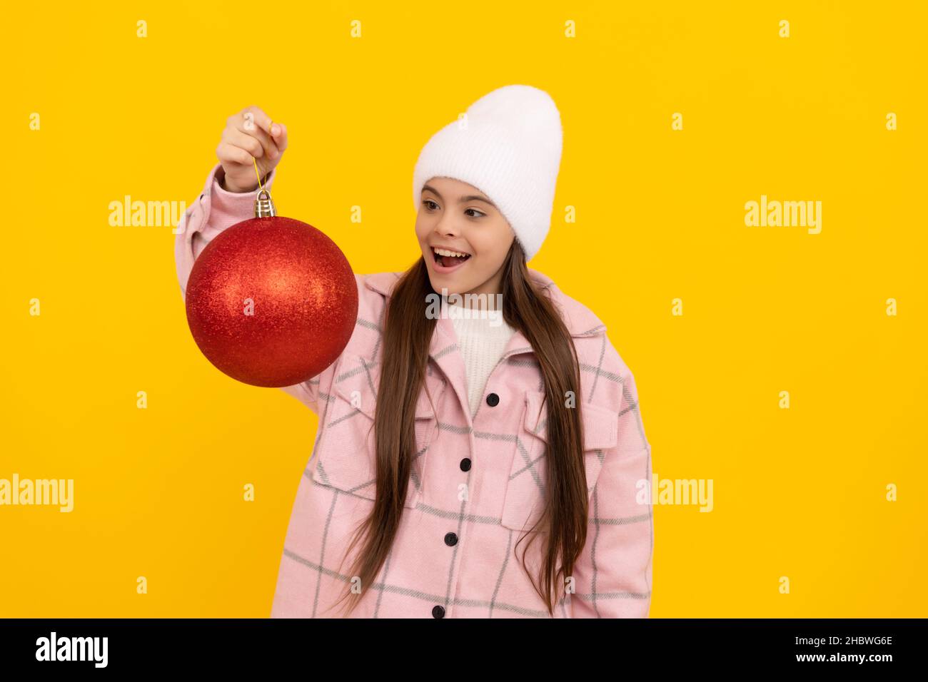 buon natale. stupito capretto in inverno. ragazza teen con sfera decorativa rossa Foto Stock