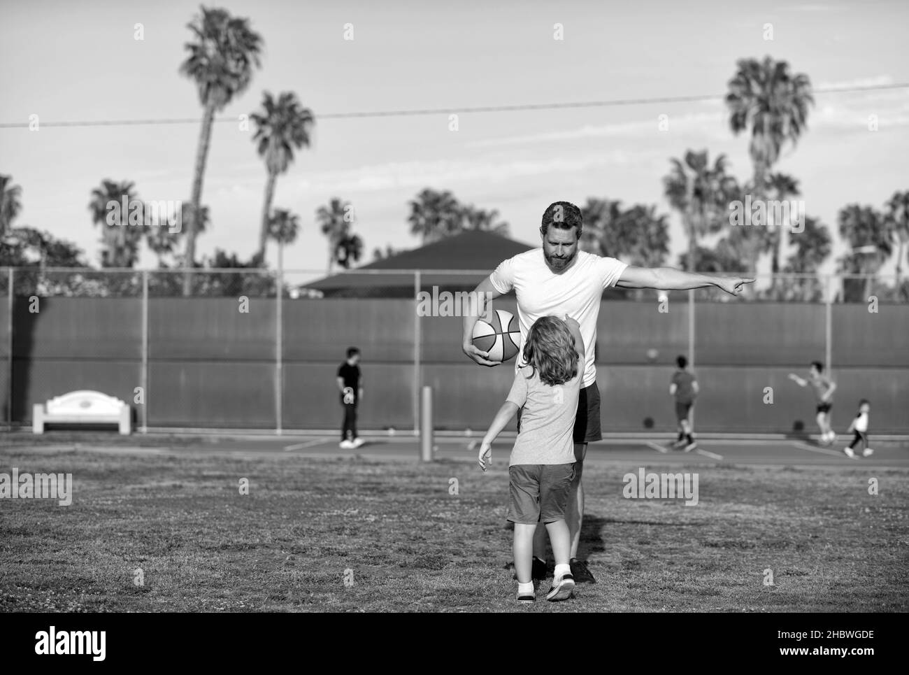 Bambino ragazzo ascoltare l'addestratore dell'uomo che spiega le regole di pallacanestro sul terreno di sport, l'addestramento di sport Foto Stock