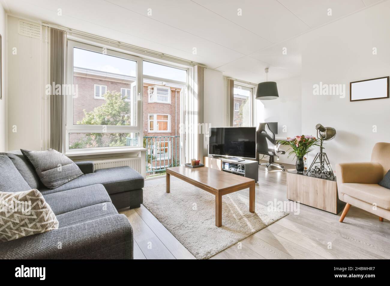 Accogliente soggiorno con divano nero e tavolino in legno Foto Stock