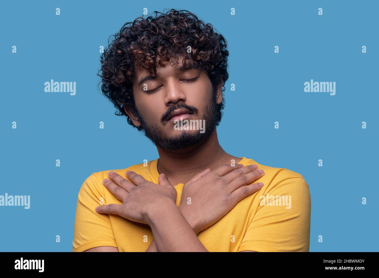 Calmo ragazzo indiano con le braccia incrociate sul petto Foto Stock
