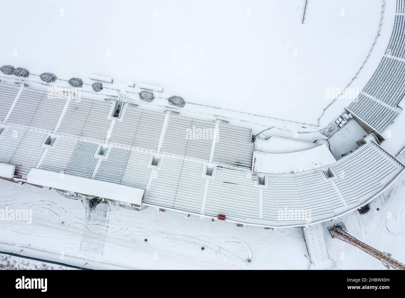 stadio di calcio vuoto nella stagione invernale. posti a sedere e campo di calcio coperti di neve. vista aerea dall'alto. Foto Stock