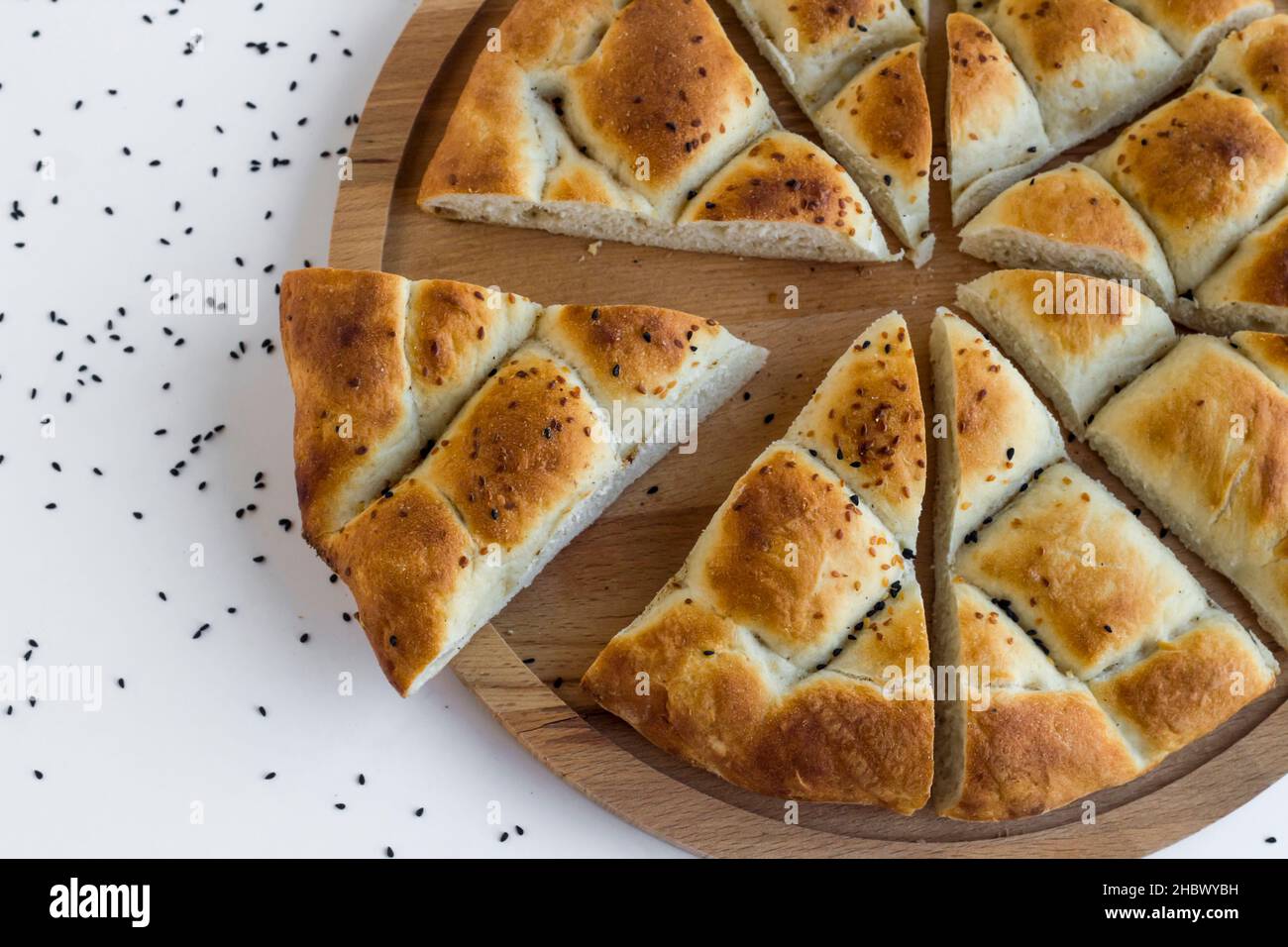 Pane ramadan a fette triangolare, pide sul piatto di legno con semi di sesamo e nigella, vista dall'alto. Foto Stock