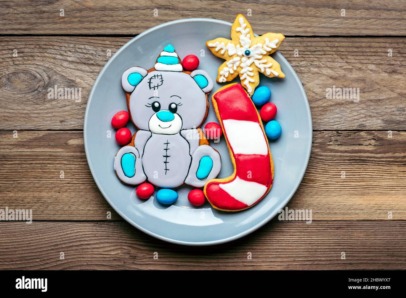 Biscotti di pan di zenzero decorati con glassa a forma di orso in cappello, lecca lecca, fiocchi di neve sul piatto su sfondo rosso Vista dall'alto piatto posare le delizie di Natale Foto Stock