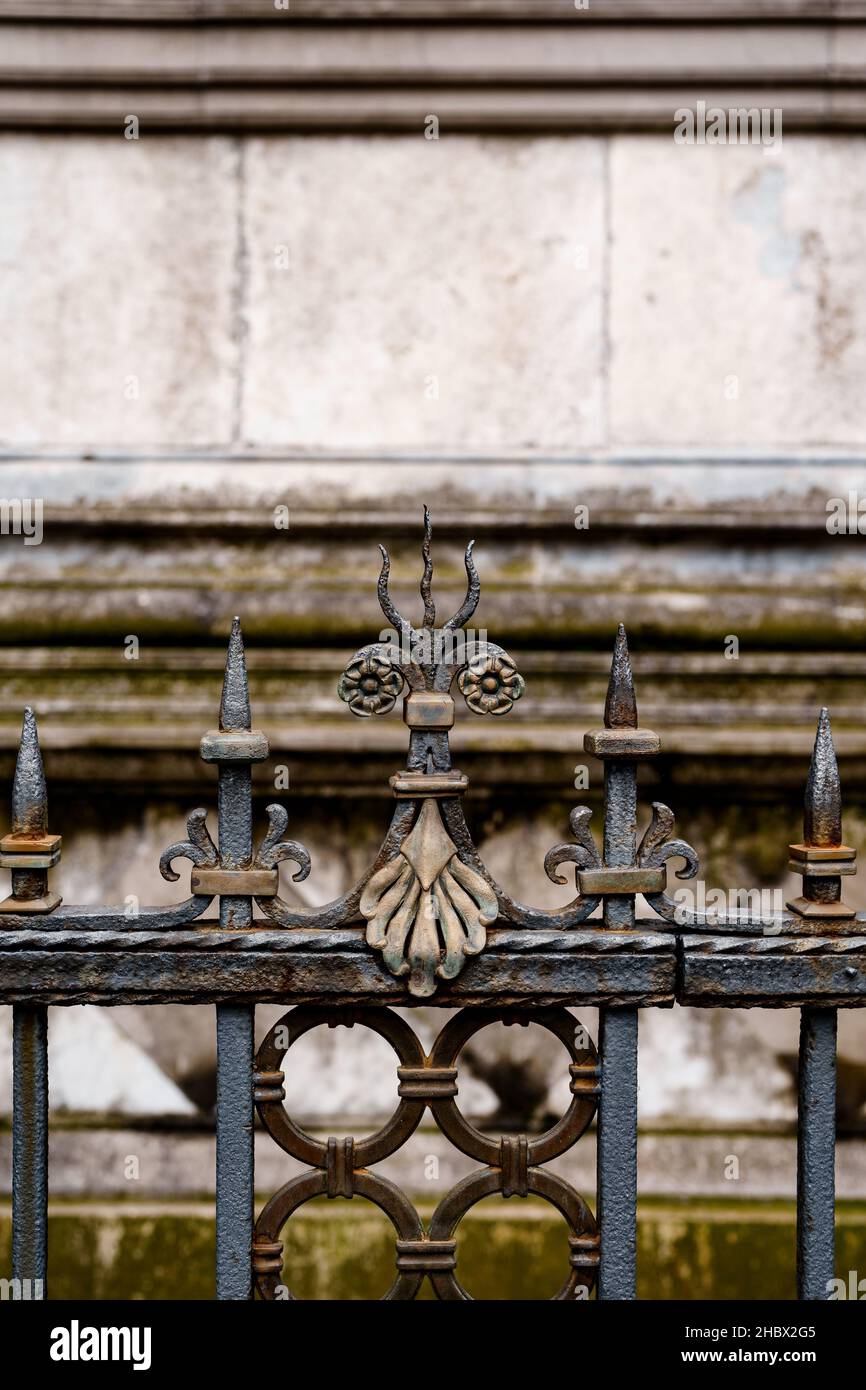 Pommel in metallo con fiori e un tridente ondulato su una recinzione in ferro battuto. Primo piano Foto Stock