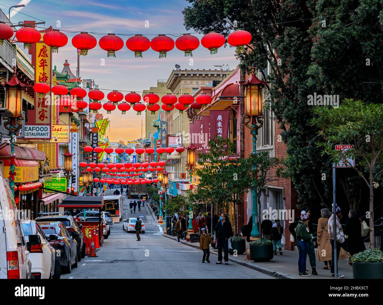 San Francisco, USA - 18 dicembre 2021: Negozi tradizionali, lanterne e gente in strada a Chinatown vicino al centro con un tramonto ardente Foto Stock