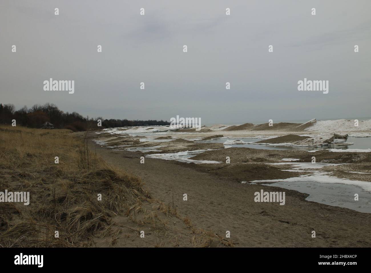 Una spiaggia sabbiosa e sporca e grandi onde che vengono dal mare catturate durante il tempo tempestoso Foto Stock