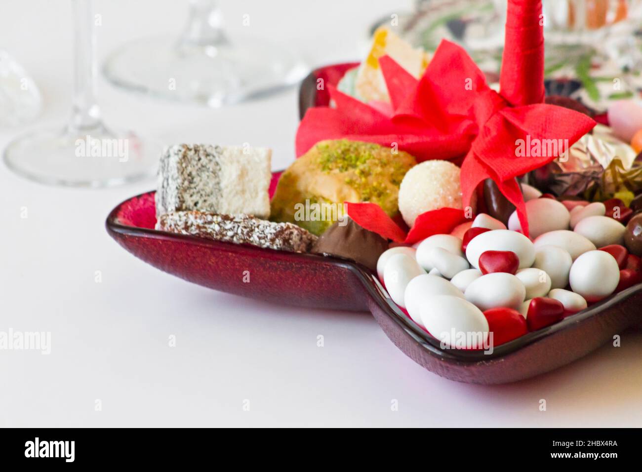 Dolci turchi tradizionali, Baklava, Lokum e caramelle sono disegnati su un piatto a forma di stella con nastro rosso Foto Stock