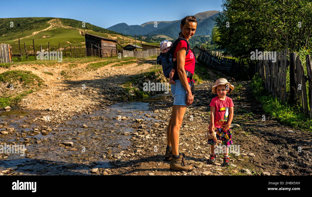 Madre, figlia giovane e figlio di un bambino in una portavaluette durante un viaggio in montagna. Foto Stock