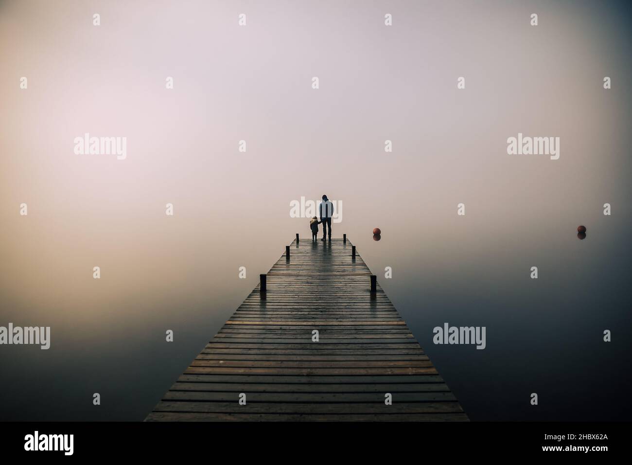 Bella nebbia suggestiva mattina nel Lake District con padre e figlio Foto Stock