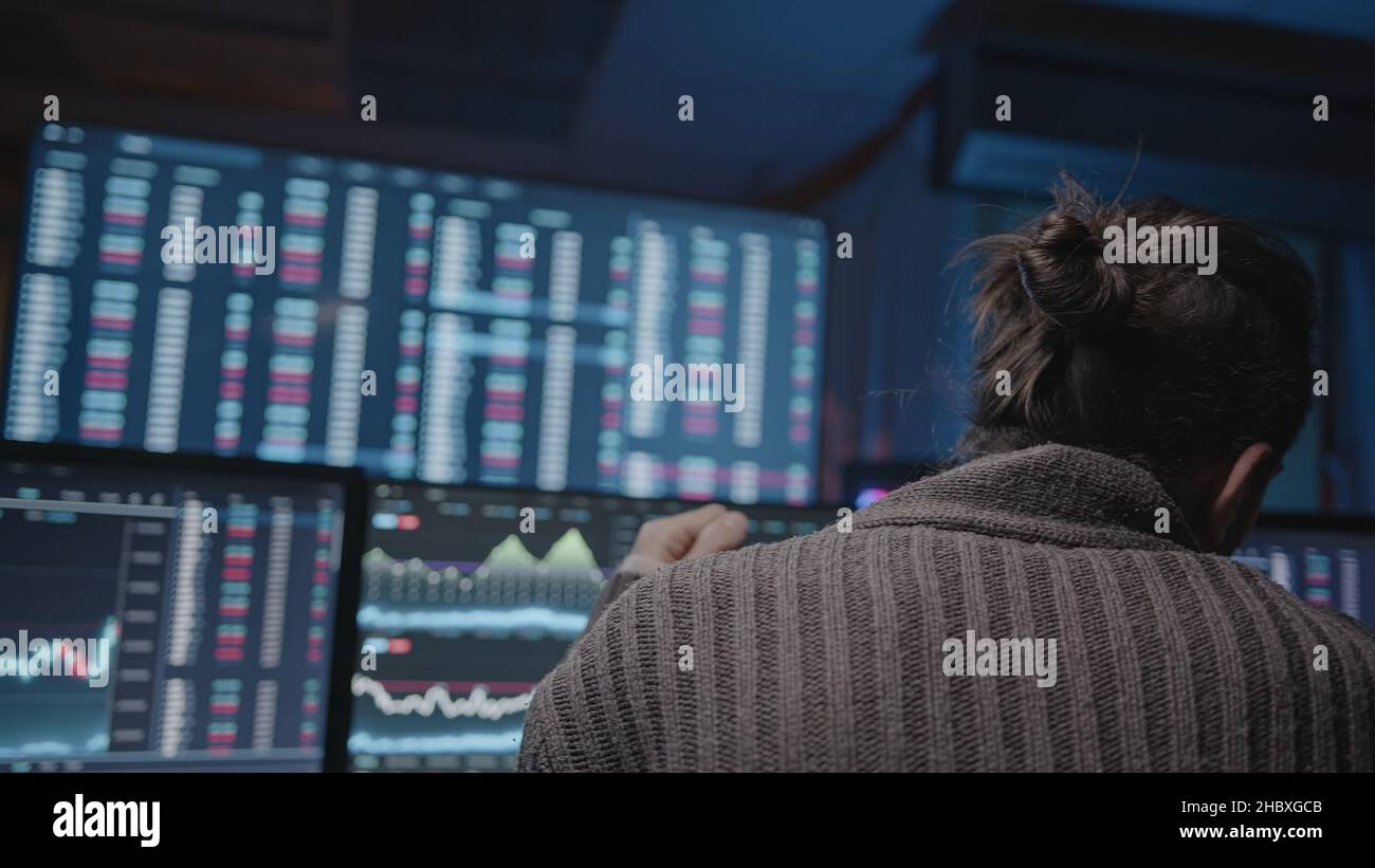 Uomo con barba lunga e capelli lunghi che fa l'analisi per il commercio di giorno su schermi di analisi di criptovaluta Foto Stock