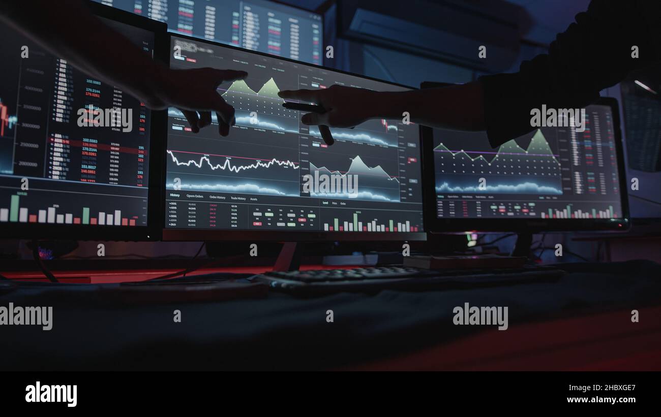 Due economisti maschili professionisti che guardano i grafici azionari sui monitor che eseguono l'analisi AltCoin Foto Stock