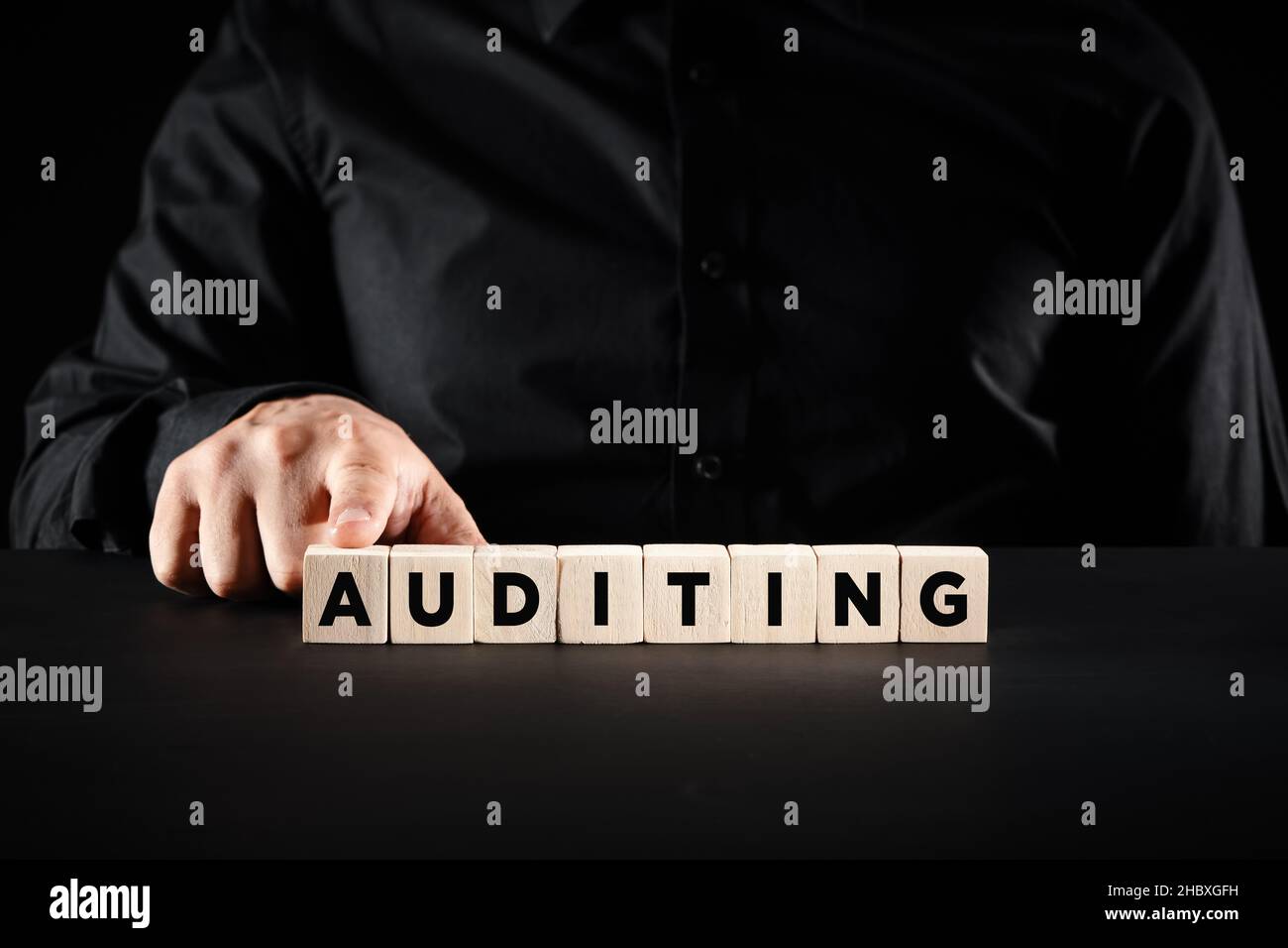 La mano maschio spinge i blocchi di legno con la parola auditing. Concetto di audit finanziario aziendale. Foto Stock