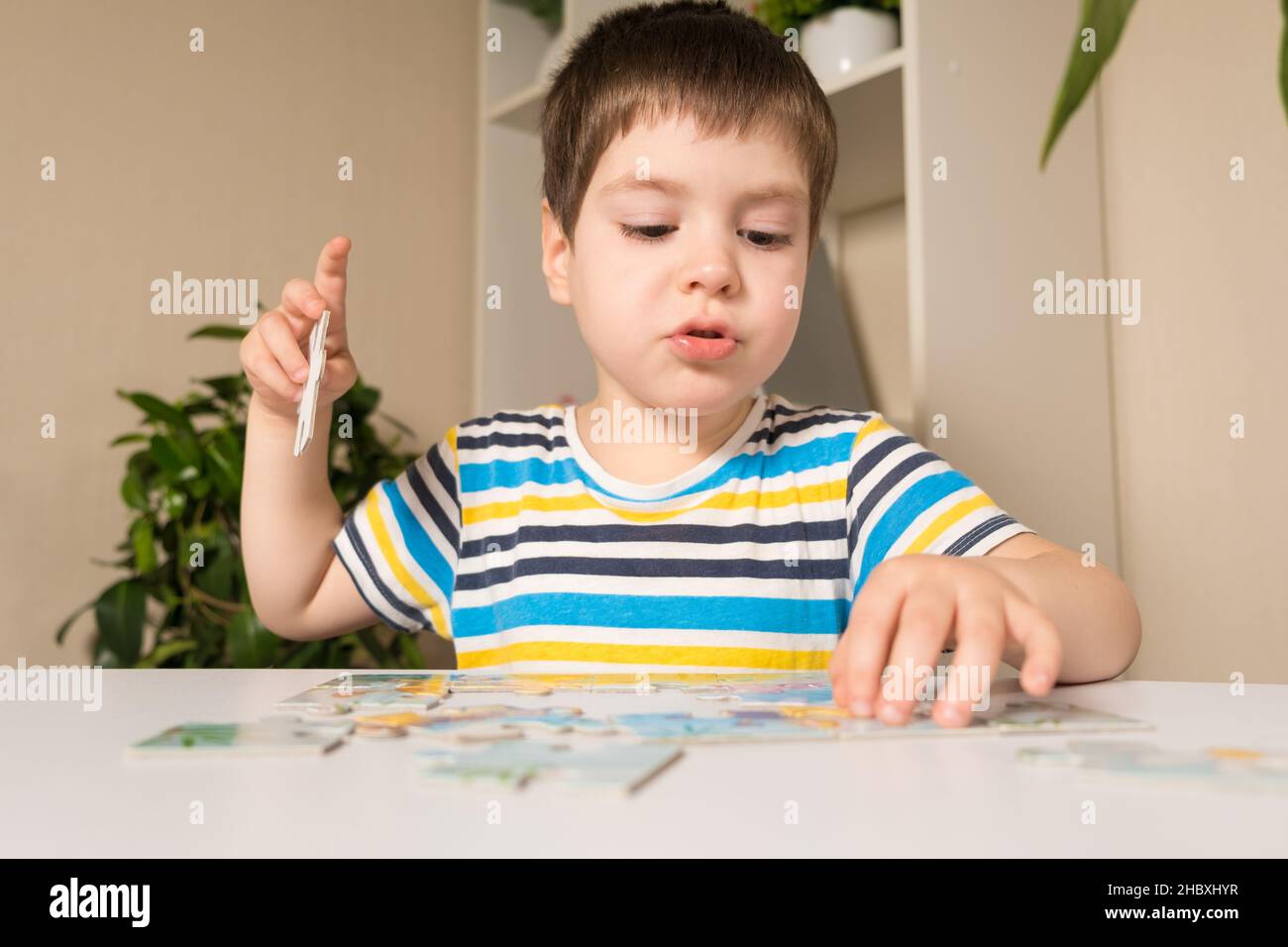 Un preschooler suona puzzle, mette insieme un'immagine Foto Stock