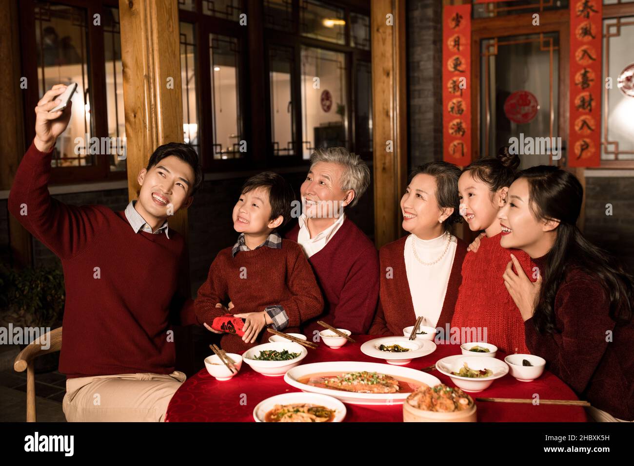 Famiglie felici che prendono selfie con il loro telefono cellulare durante il cenone di Capodanno Foto Stock