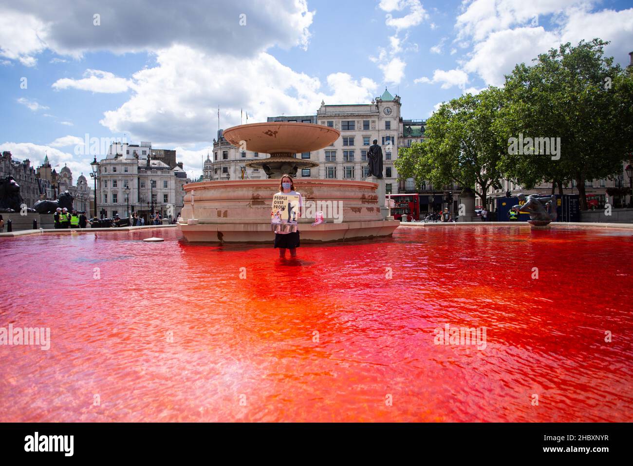 Attivista della ribellione degli animali in piedi in acqua rossa nella fontana di Trafalgar Square che tiene sangue sulle mani placard London 2020 Foto Stock