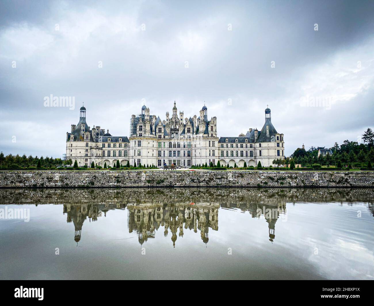 Vista grandangolare del Castello di Chambord nella valle della Loira, con i suoi giardini, giorno nuvoloso, riflessione d'acqua, Francia Foto Stock