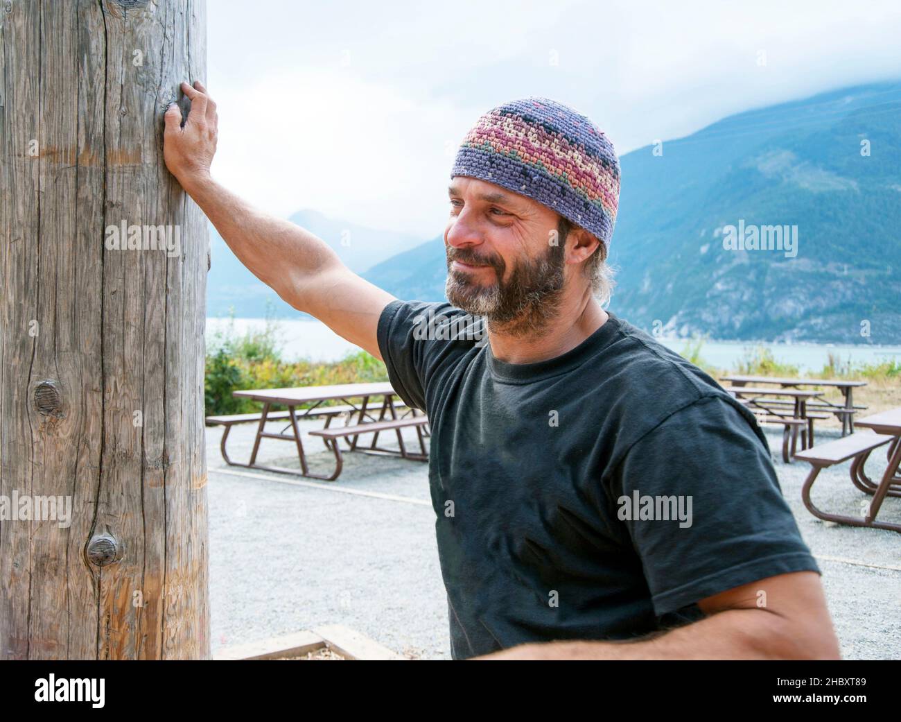 Uomo in zona pic-nic tra le montagne indossare cappello a maglia. Foto Stock