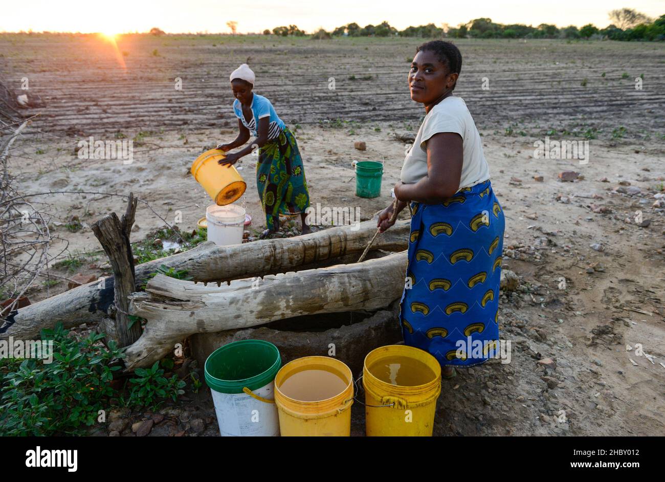 ZAMBIA, Mazabuka, zona di Chikankata, casa, le donne prelevano acqua dal pozzo al crepuscolo / SAMBIA, Mazabuka, zona di Chikankata, Bauernhof, Frauen holen Wasser vom Brunnen Foto Stock