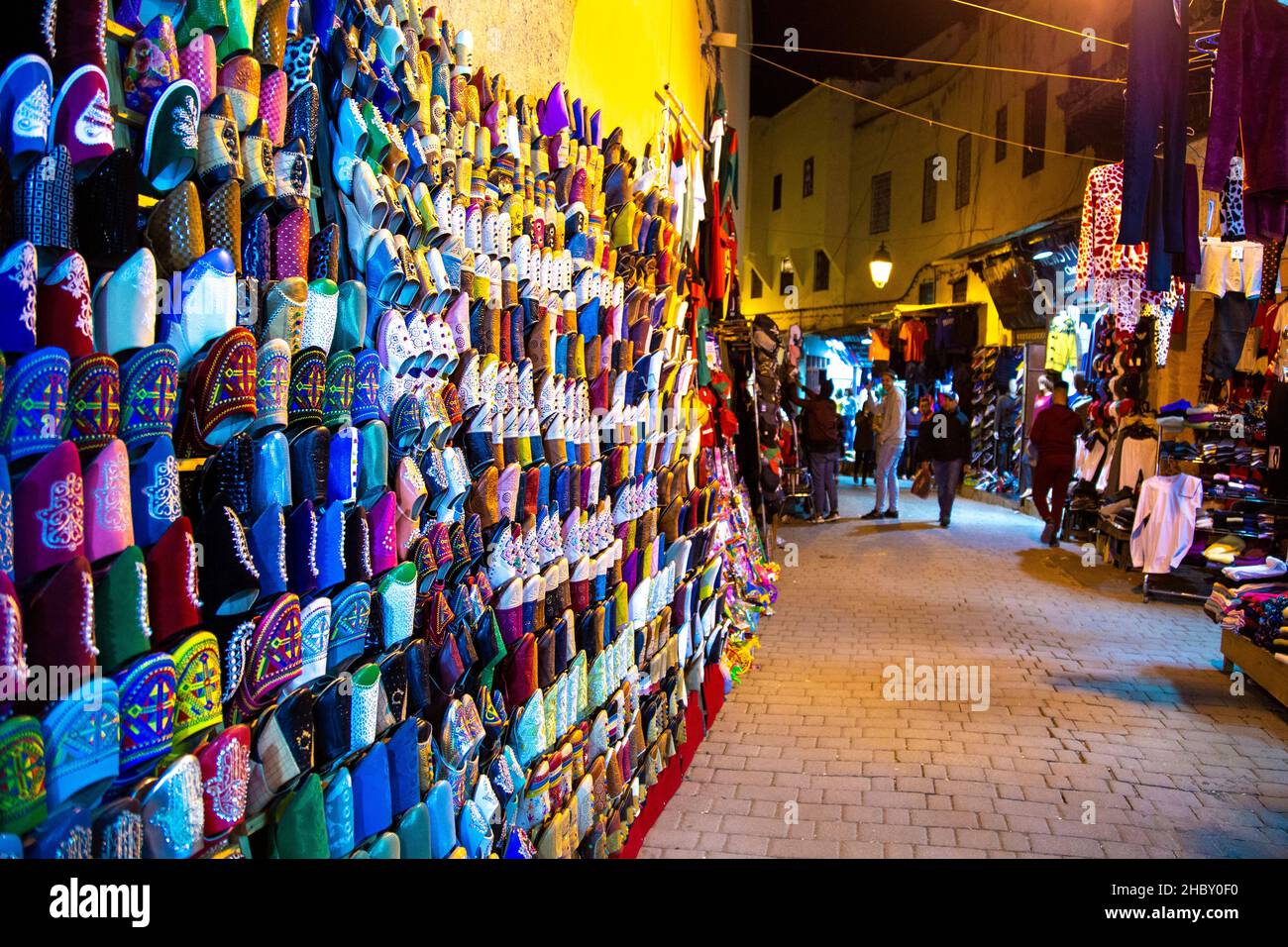 Ciabatte marocchine, strada stretta con bancarelle di mercato e negozi nei souk della medina, Fes, Marocco Foto Stock