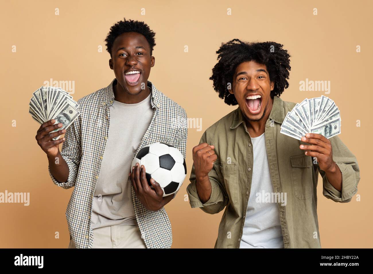 Scommesse sportive. Ritratto dei neri eccitati con pallone da calcio e denaro Foto Stock