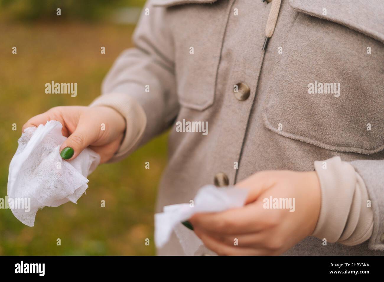 Primo piano scatto ritagliato di donna irriconoscibile che tiene panni antibatterici bagnati per pulire e disinfettare le mani all'aperto. Foto Stock