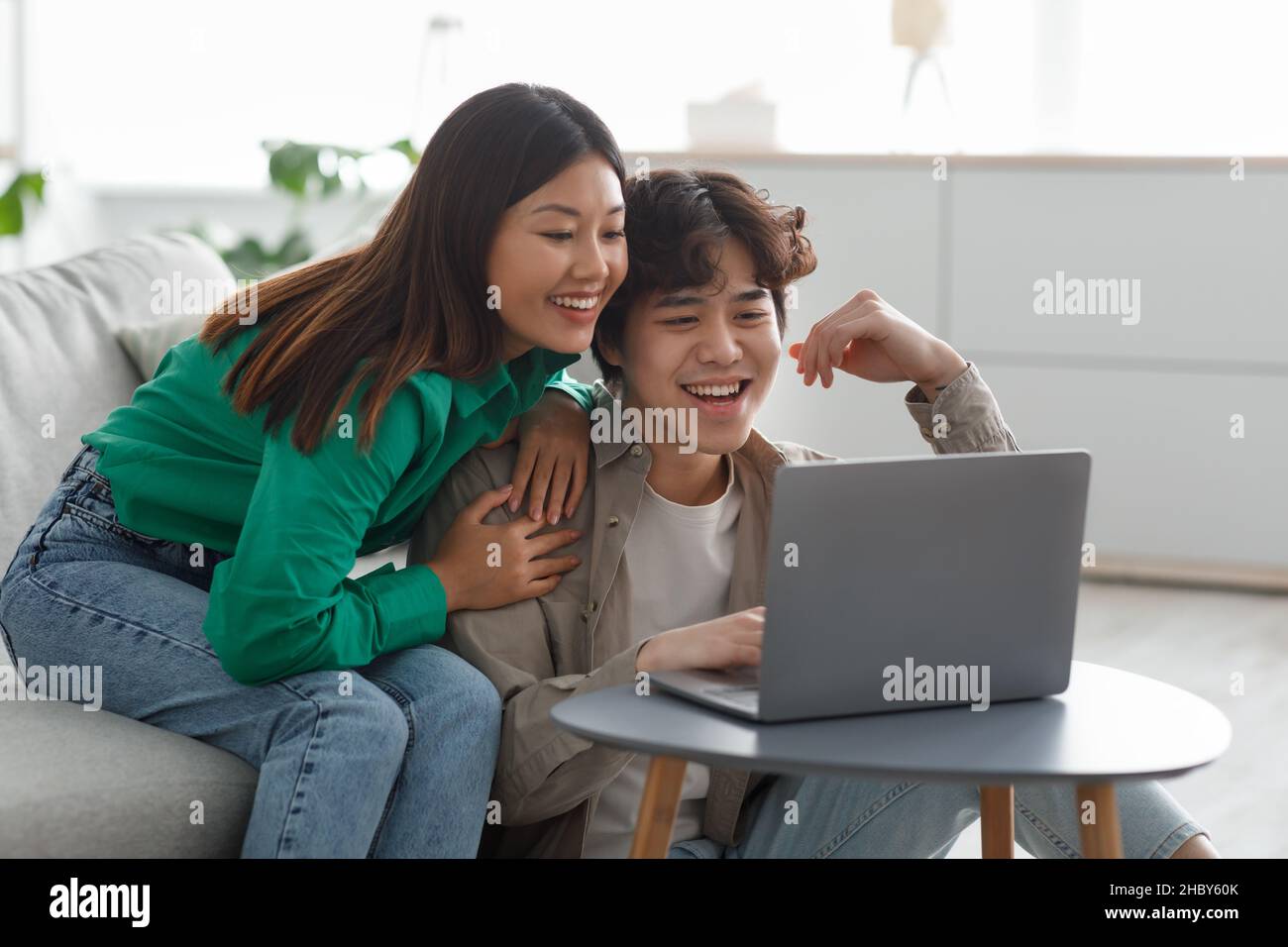 Coppia asiatica millenaria in abbigliamento casual utilizzando un laptop,  avendo incontri online, guardando un interessante film in salotto Foto  stock - Alamy