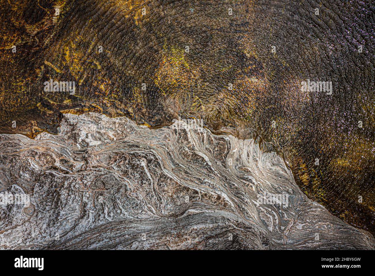 Vista dall'alto dell'acqua di un fiume e di una sponda rocciosa. Il vento dà al tutto una texture superba. Foto Stock