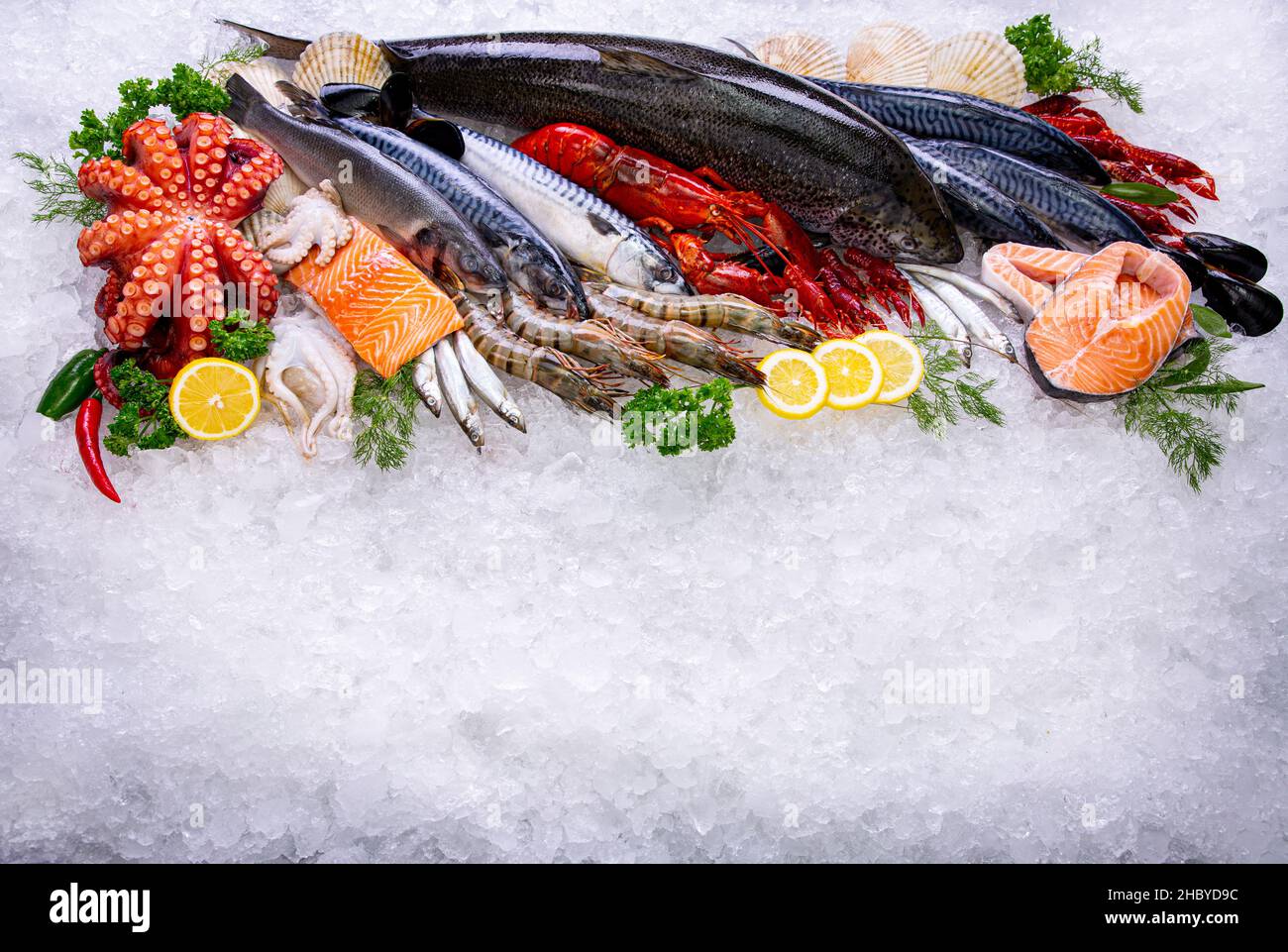 Frutti di mare materia prima con vista dall'alto sul ghiaccio. Vista dall'alto cibo mediterraneo surgelato e erbe aromatiche come limone, aneto, prezzemolo. Foto Stock