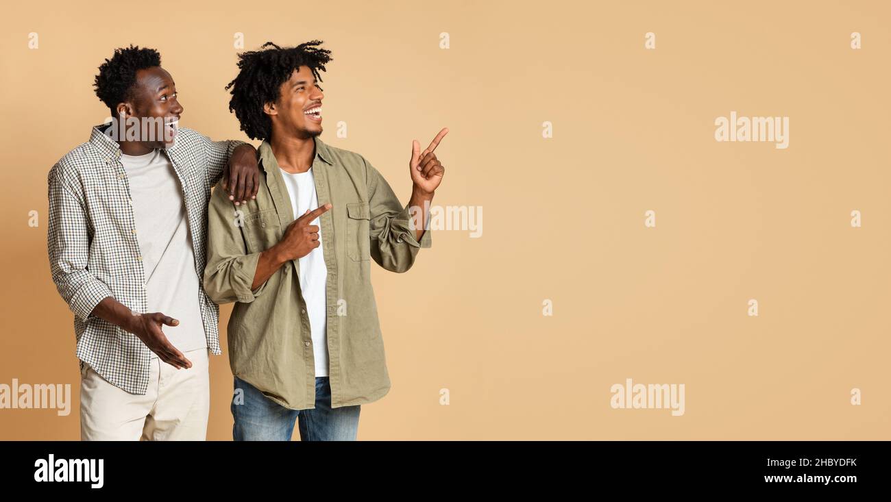 Controllare. Due ragazzi africani che guardano e puntano da parte a Copy Space Foto Stock