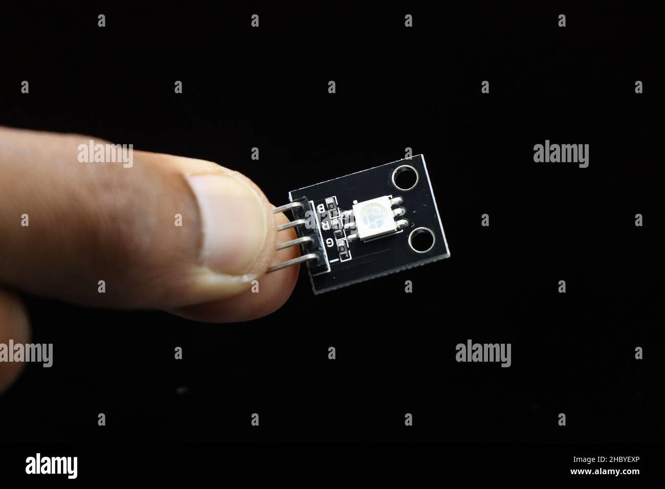 Modulo LED SMD a tre colori per schede microcontroller programmabili tenute in mano isolate su sfondo nero Foto Stock