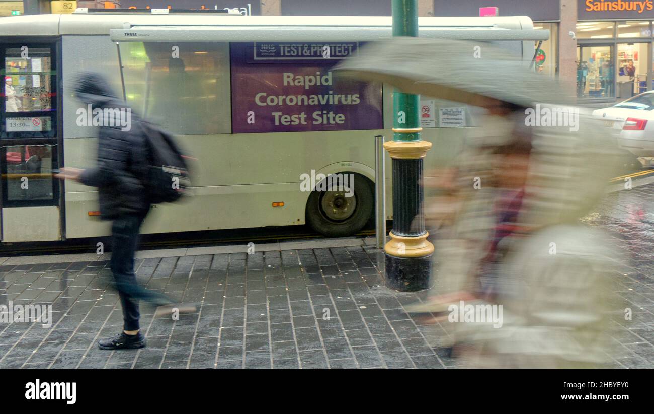 Glasgow, Scozia, Regno Unito 22nd dicembre 2021. UK Weather: Wet covid Christmas Streets ha visto la gente del posto lottare sotto la pioggia con i segni di Natale tutto intorno a loro la stazione ferroviaria centrale ha visto i tester covid in forve come una sede tarheted infornation..Credit Gerard Ferry/Alamy Live News Foto Stock