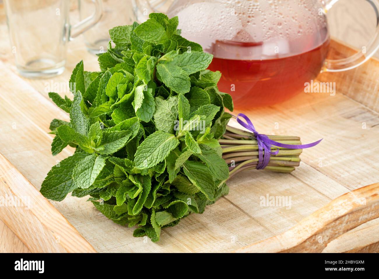 Bouquet di menta verde fresca con una teiera di vetro e tè sullo sfondo Foto Stock
