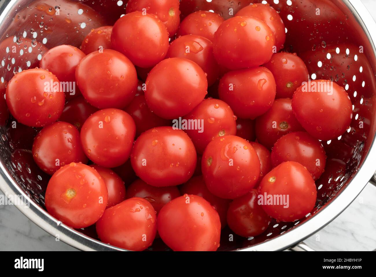 Pomodori rossi freschi lavati in un colino metallico Foto Stock