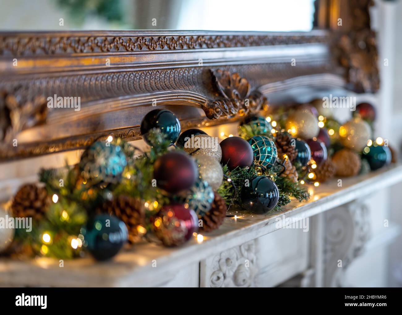 Belle decorazioni natalizie tradizionali e luci rosso baubles pino abete rami su fregio. Accesa con luci natalizie per la stagione delle feste Foto Stock