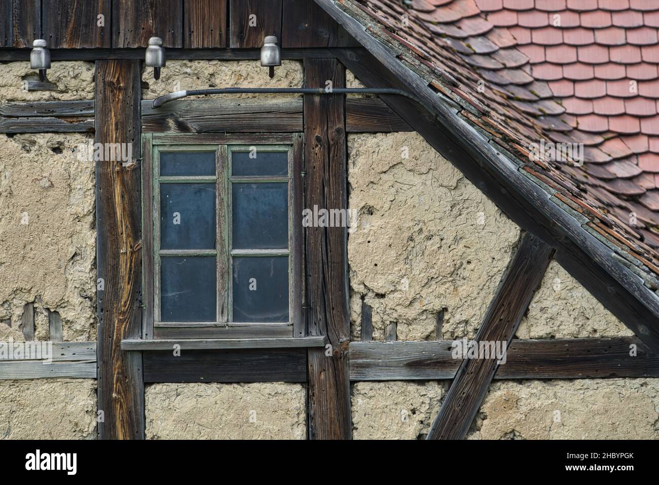 Alter Fachwerkgiebel Ausschnitt mit Lehm ausgefacht altes Fenster und Dachziegeln Foto Stock