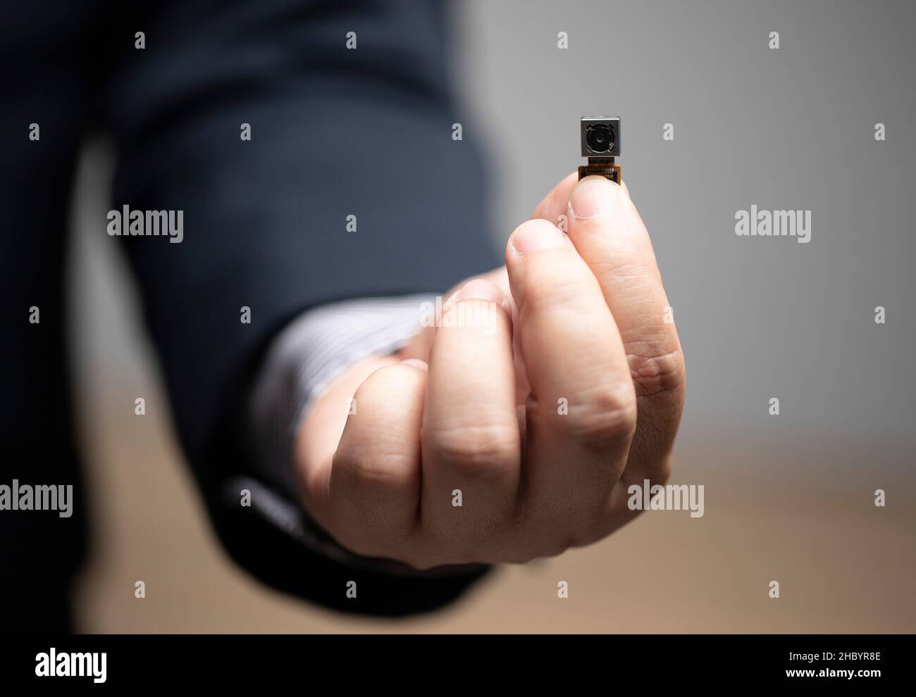 Sicurezza legale, telecamera pinhole, privacy dei dati personali, uomo d'affari che tiene la telecamera pinhole in mano. Foto Stock