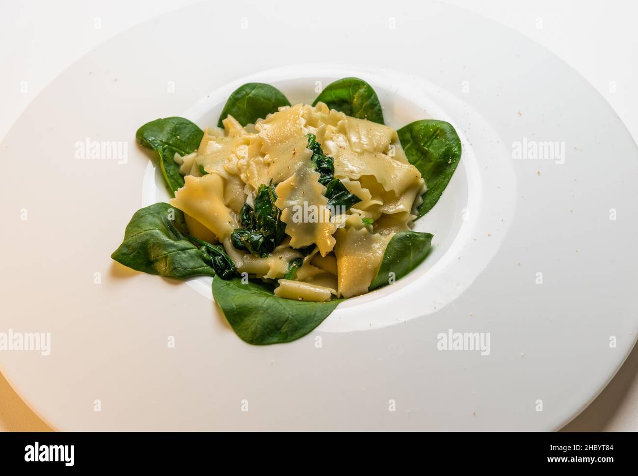Pasta Maltagliati con spinaci e salsa al burro, primo piano in piatto bianco Foto Stock