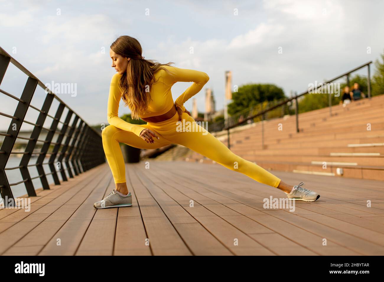 Bella giovane donna che ha stretching esercizio sul molo sul fiume Foto Stock