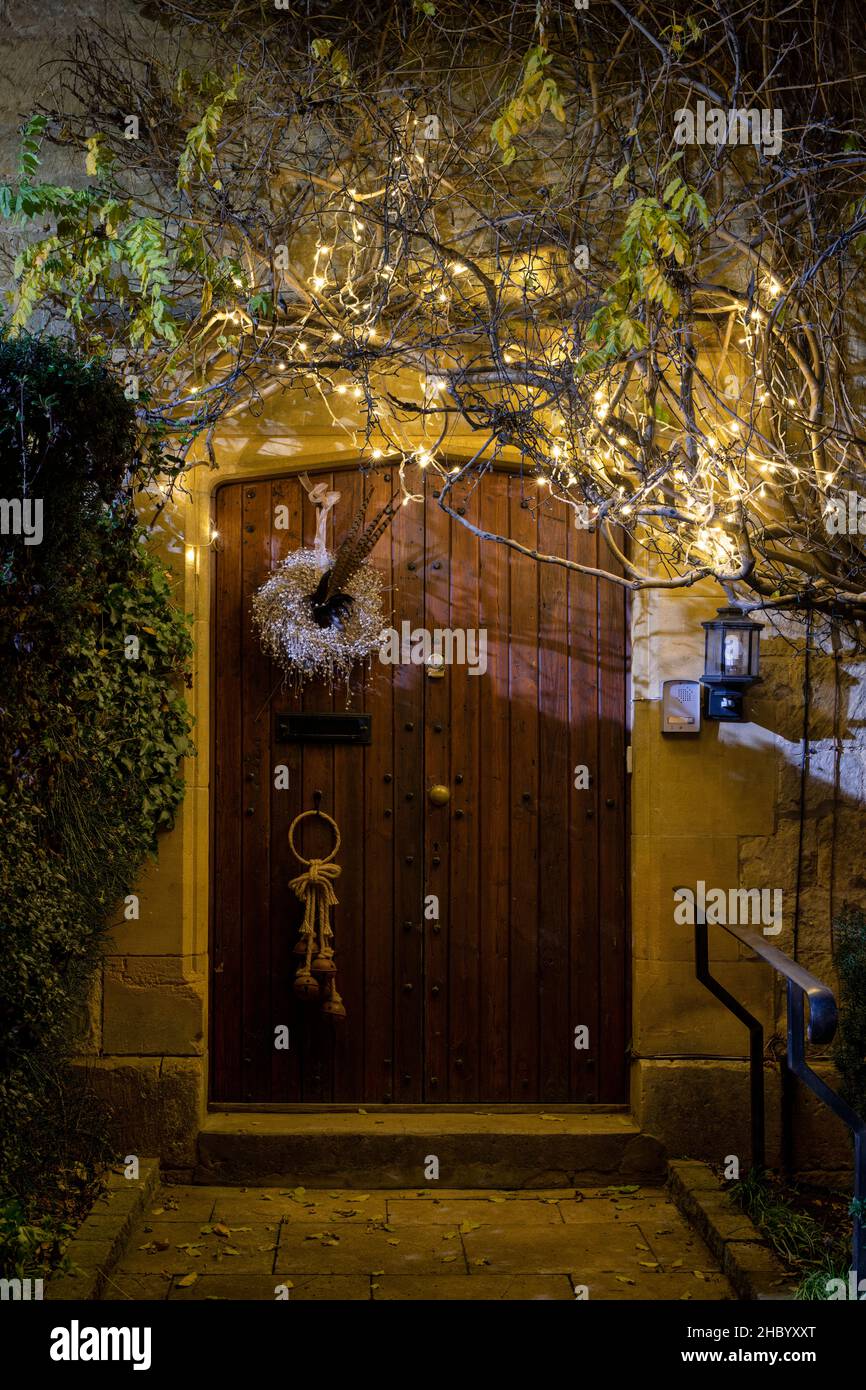 Luci di Natale sopra la porta di una casa di notte. Chipping Campden, Cotswolds, Gloucestershire, Inghilterra Foto Stock