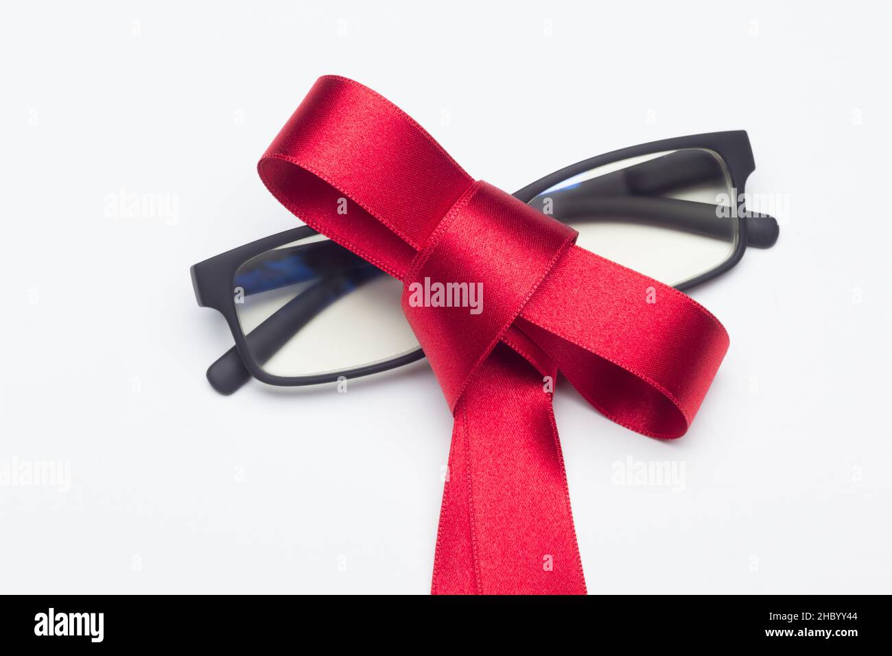 Bicchieri neri con arco rosso da regalare su sfondo bianco Foto Stock