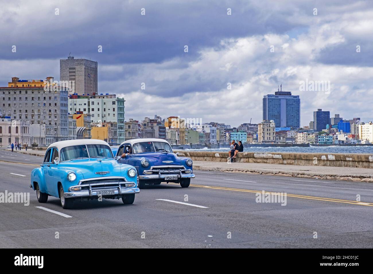 Due auto d'epoca Chevrolet 1950s sul Malecón / Avenida de Maceo, viale e muro di mare lungo la città Havana sull'isola Cuba Foto Stock
