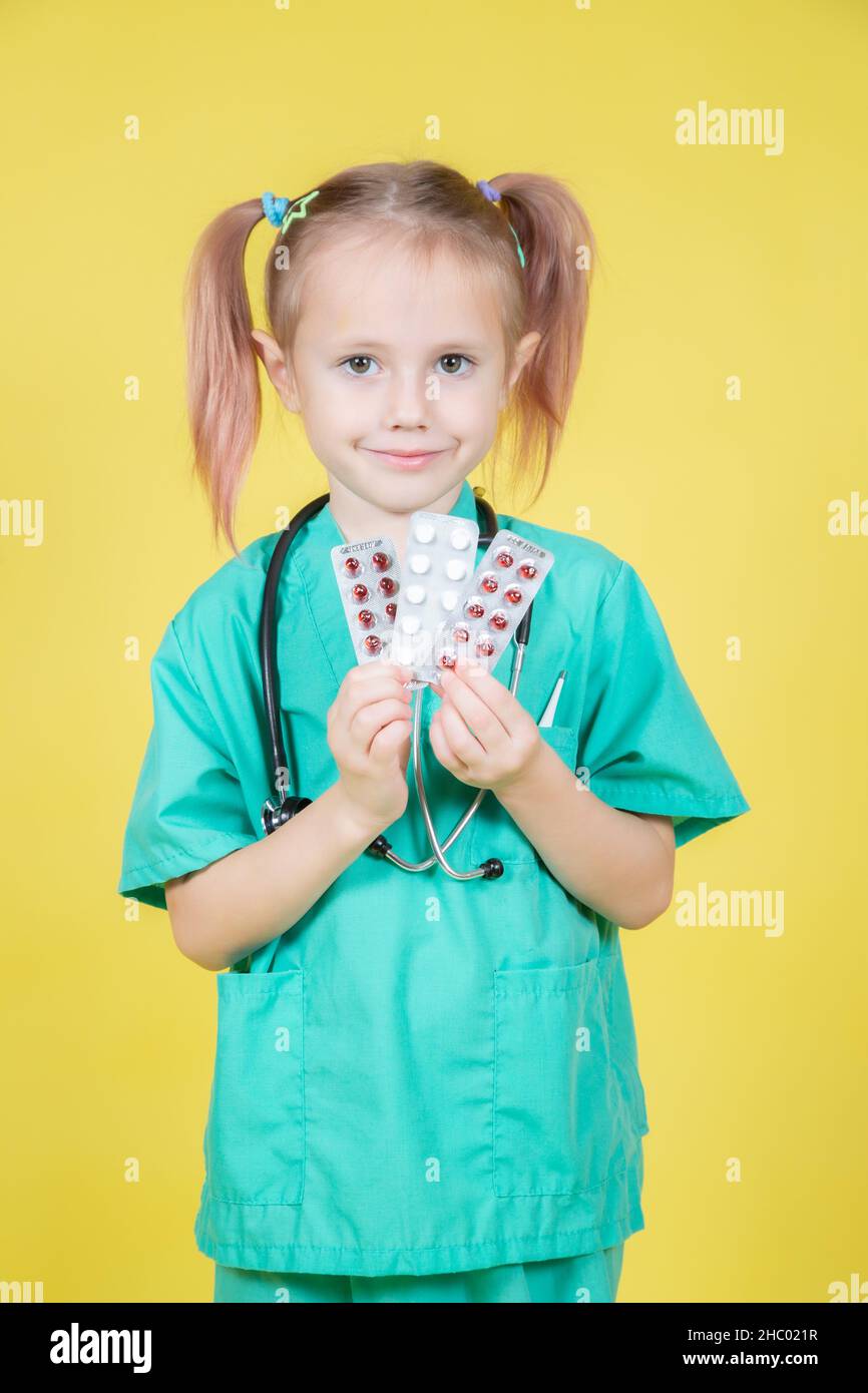 Ritratto di bambina vestita in camice medici contiene blister con pillole Foto Stock
