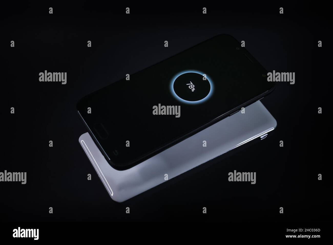 Smartphone durante la ricarica wireless da un caricabatterie su sfondo nero Foto Stock